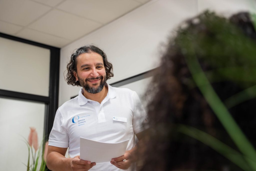 Medewerker verwelkomt een patiënt in de praktijk